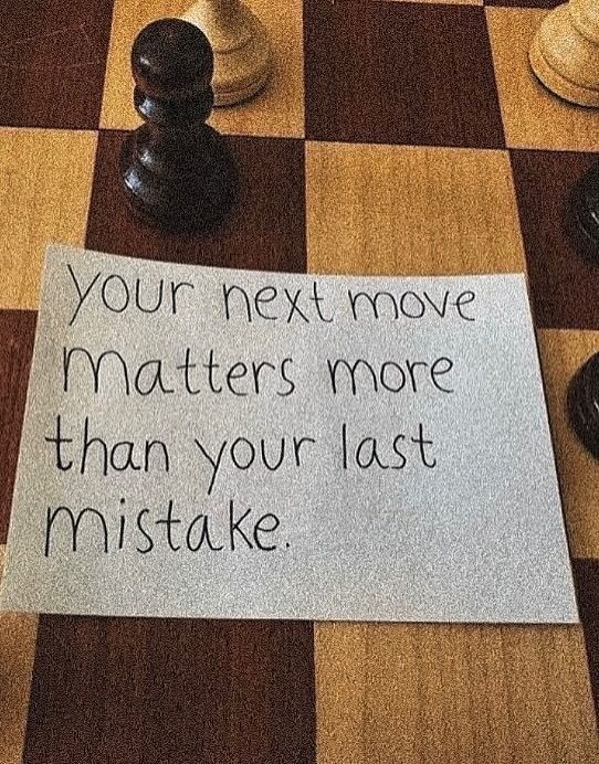 A handwritten quotation resting on a wooden chessboard.